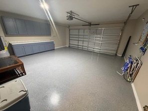 Garagem com piso de concreto e ventoinha no teto, além de porta de garagem.