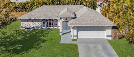A two-story house with a garage, a driveway, and a well-maintained lawn.
