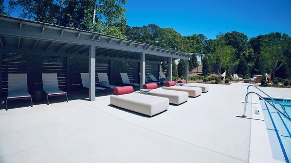 A covered outdoor pool area with lounge chairs and a pool.