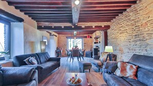 A cozy living room with leather sofas, a wooden coffee table with fruit, and a stone wall. - Nice home in Baraque de Fraiture with sauna (Baraque de Fraiture)