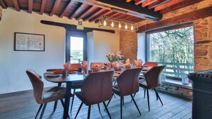 A dining area with a wooden table, chairs, and a view through a window. - Nice home in Baraque de Fraiture with sauna (Baraque de Fraiture)