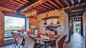 A rustic dining area with stone walls, wooden beams, and a fireplace. - Nice home in Baraque de Fraiture with sauna (Baraque de Fraiture)