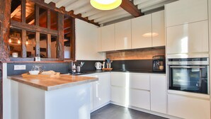 A modern kitchen with white cabinets, a wooden island, a built-in oven, and a coffee machine. - Nice home in Baraque de Fraiture with sauna (Baraque de Fraiture)