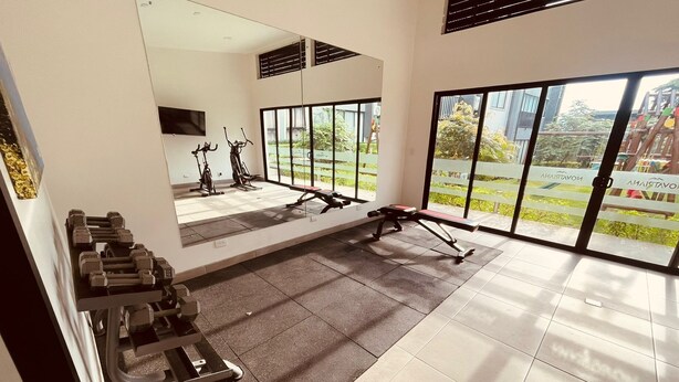 A modern gym with exercise equipment, large windows, and a view of the outdoors.