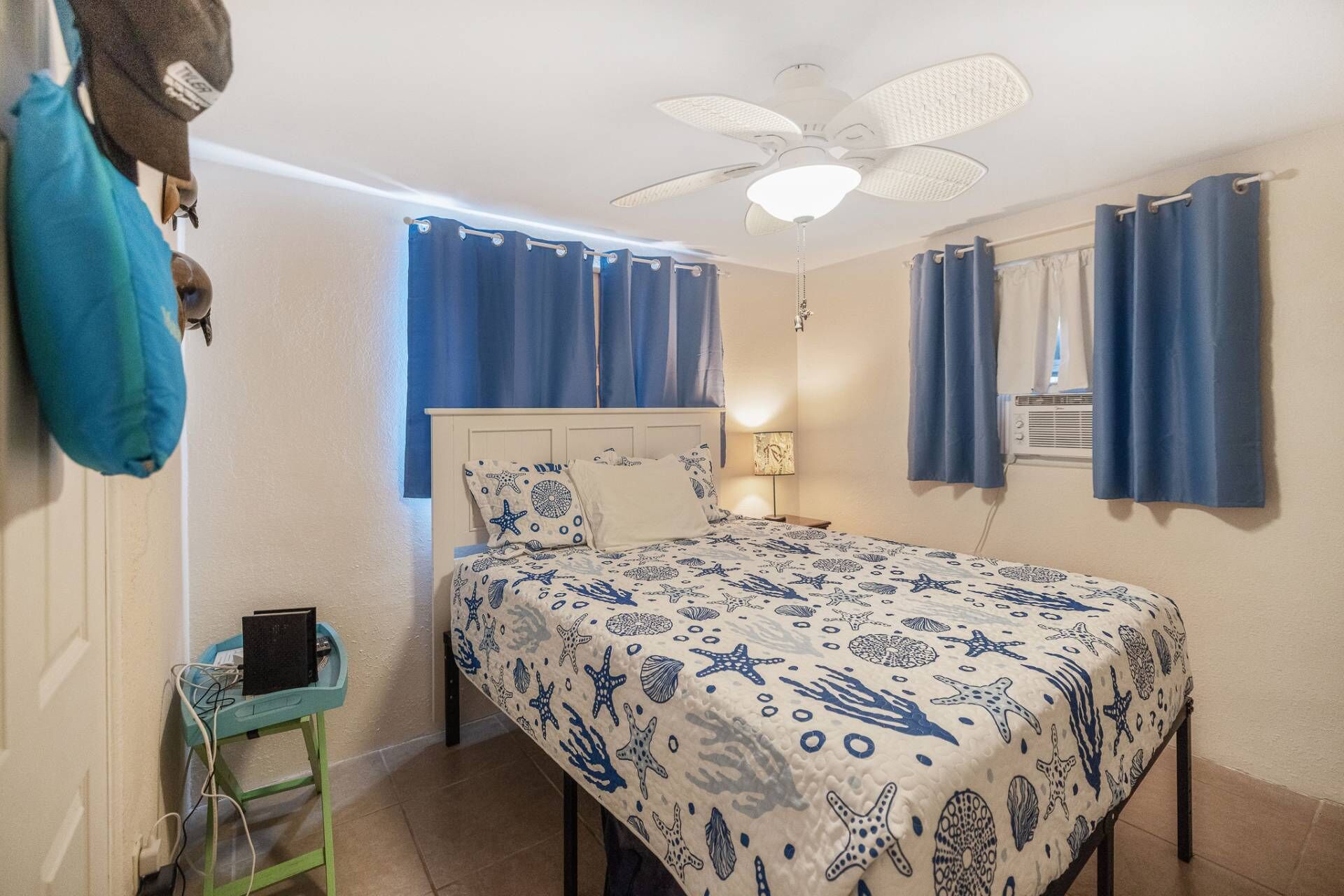 A bedroom with a bed, a ceiling fan, a nightstand, and a window with curtains.
