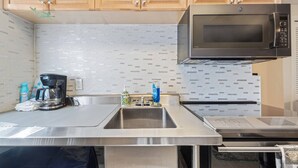 Une cuisine moderne avec des plans de travail en acier inoxydable, un four à micro-ondes intégré et des armoires en bois.