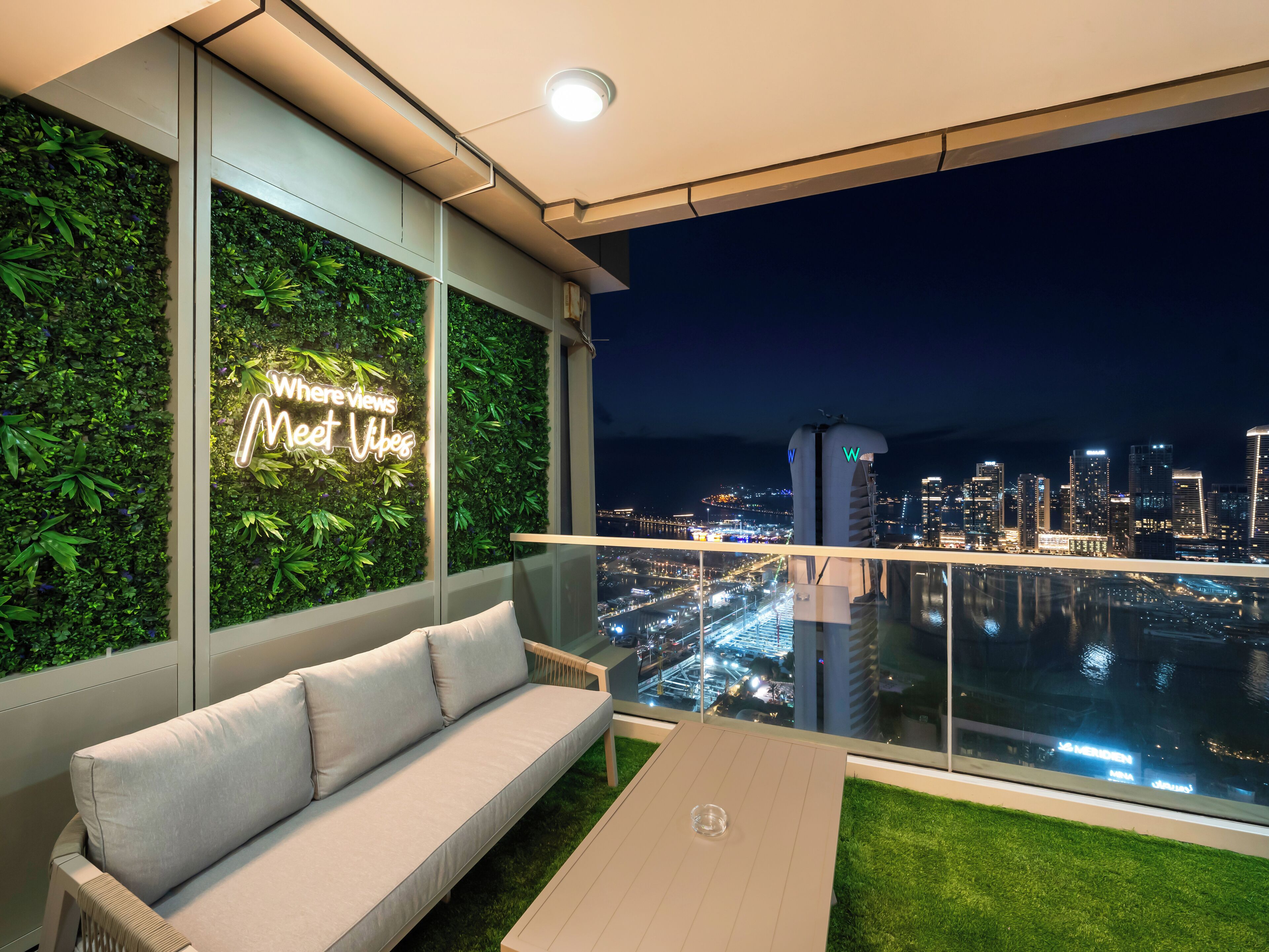 Un balcone con una divano e un neon che recita 'Where views meet vibes'.