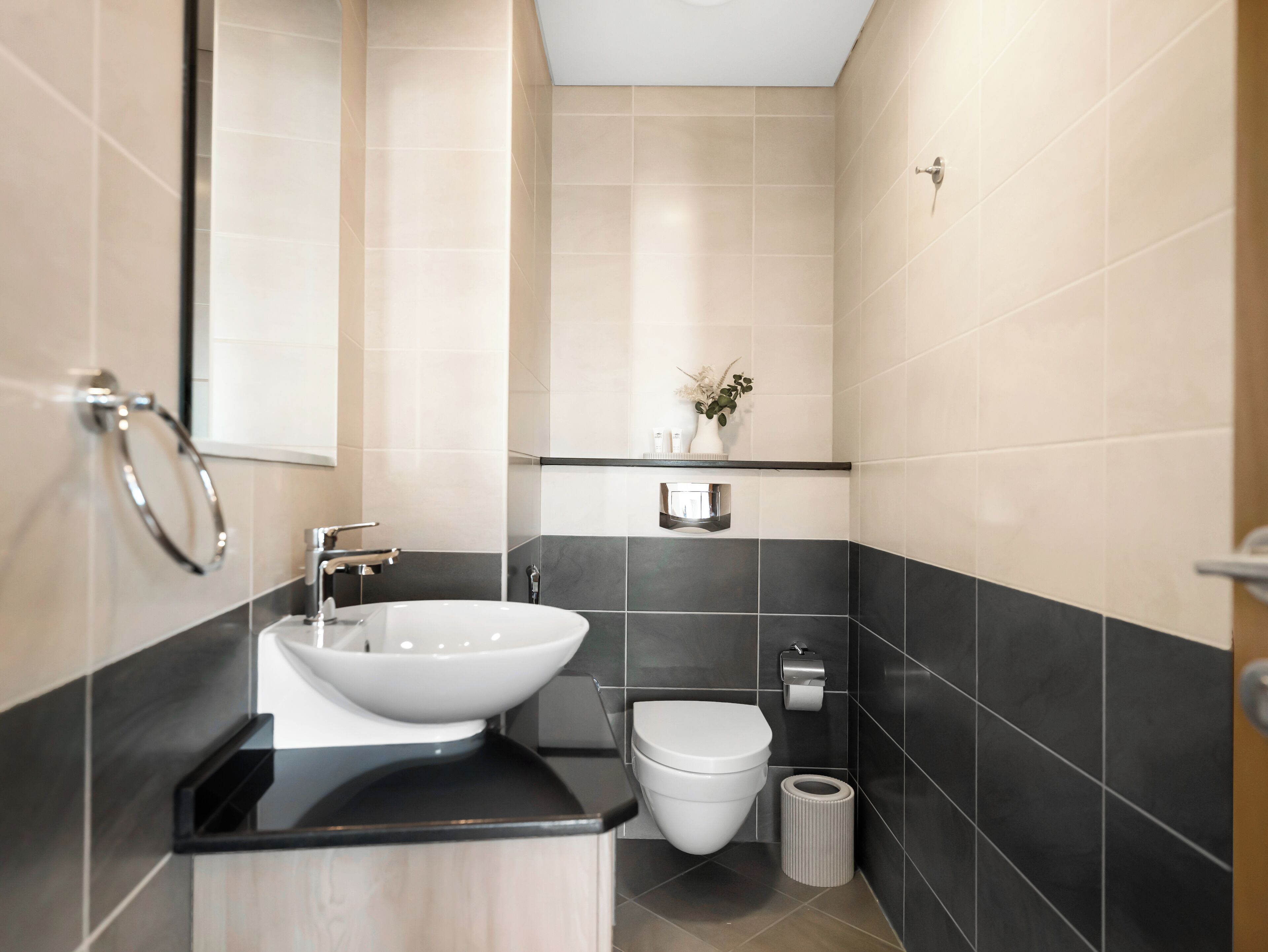 Un baño moderno con un lavabo blanco, encimera negra y un inodoro.