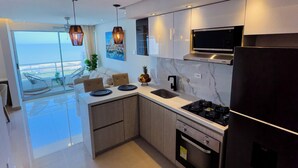 Cozinha moderna com uma ilha grande, eletrodomésticos de aço inoxidável e vista para o oceano.