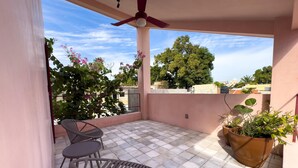A balcony with tiled flooring, a ceiling fan, and two chairs.