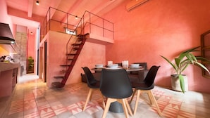 A dining area with a high ceiling, a staircase, and a dining table set with plates and glasses.