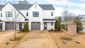 A two-story house with a grey garage door, a small brick chimney, and a well-maintained lawn. - NEW Auburn townhome perfect for families! 3/3.5 (Auburn)