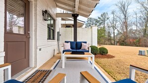 A porch with a white door, a blue sofa, and a wooden bench. - NEW Auburn townhome perfect for families! 3/3.5 (Auburn)