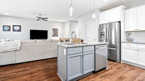 A modern kitchen with white cabinets, stainless steel appliances, and a wooden floor. - NEW Auburn townhome perfect for families! 3/3.5 (Auburn)