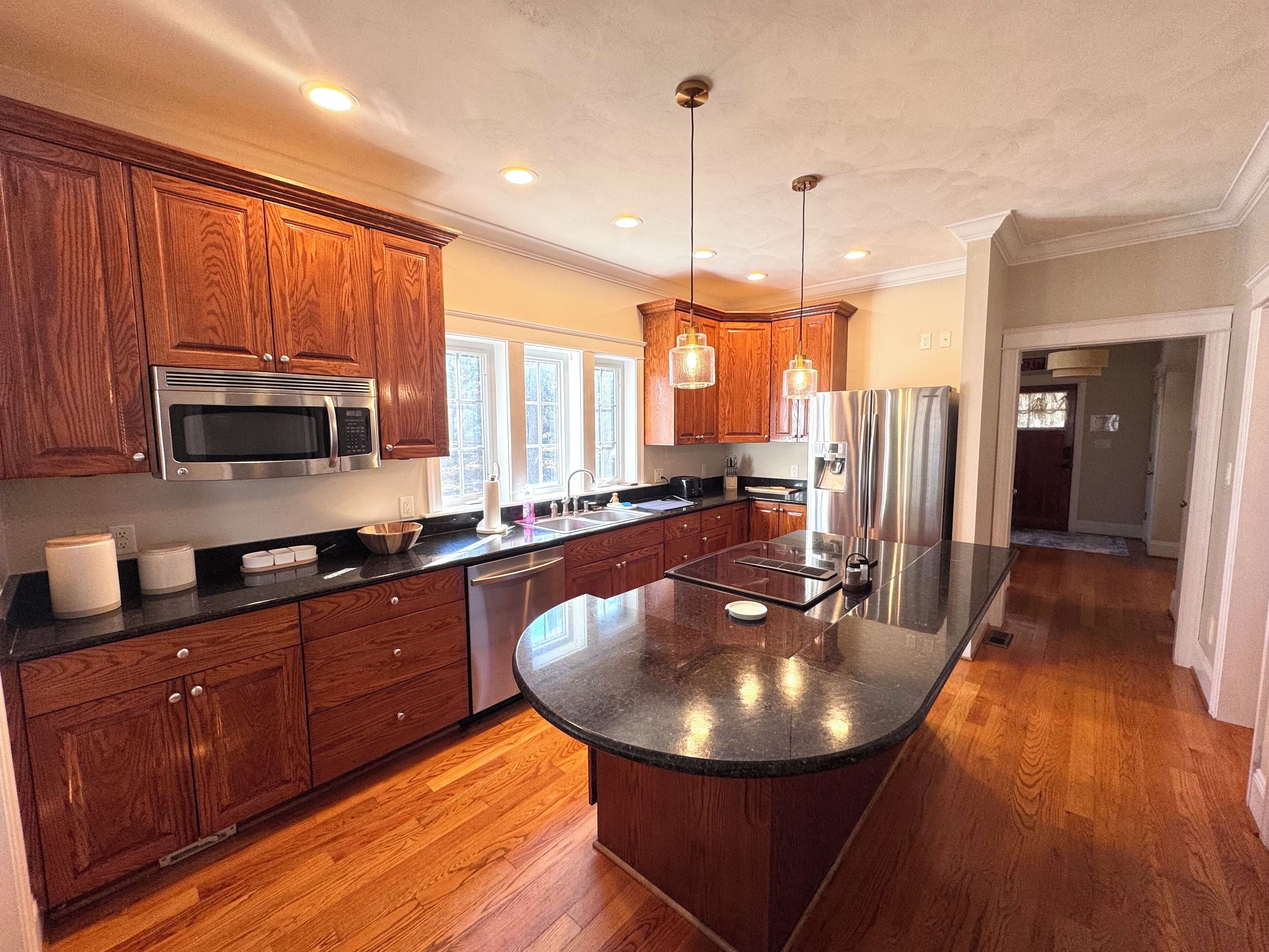 A modern kitchen with wooden cabinets, stainless steel appliances, and a large island.