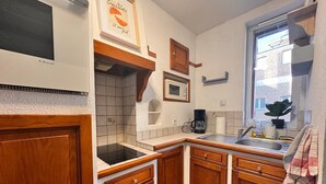 A kitchen with wooden cabinets, a microwave, a coffee maker, and a window with a plant.