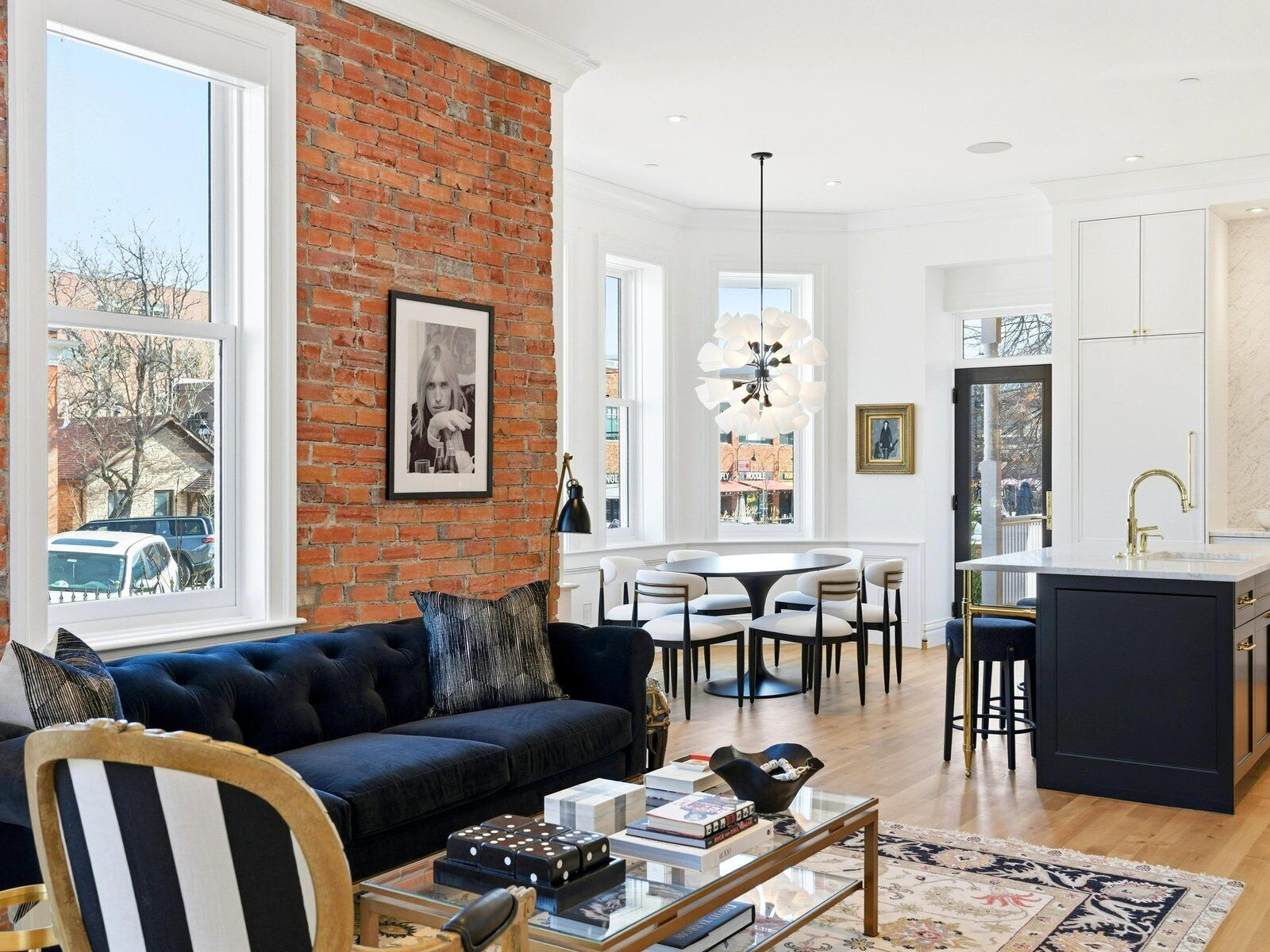 A modern living room with a dark blue sofa, a coffee table, and a view of the city through large windows.