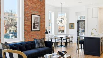 A modern living room with a dark blue sofa, a coffee table, and a view of the city through large windows.
