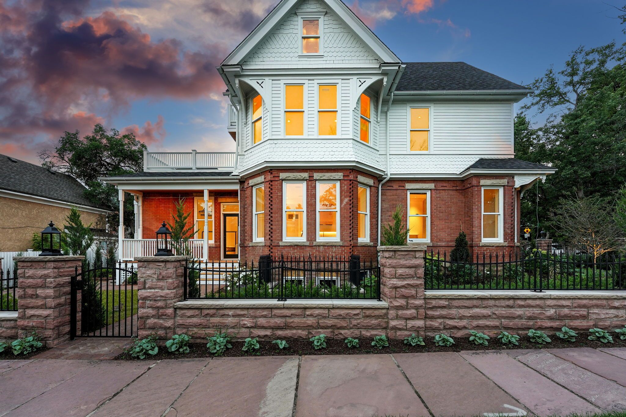 A two-story house with a prominent bay window, a brick facade, and a stone foundation.