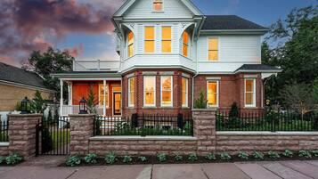 A two-story house with a prominent bay window, a brick facade, and a stone foundation.