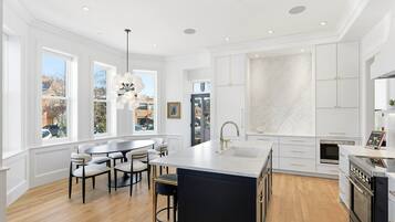 A modern kitchen with a large island, white cabinetry, and a view of the city through large windows.
