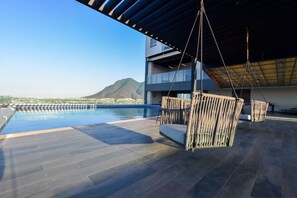 Una piscina al aire libre con vistas a una montaña y un edificio moderno al fondo.