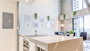 Een moderne keuken met een marmeren aanrecht, een inbouwoven en een eethoek met een tafel en stoelen.