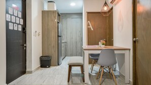 Una cucina compatta con frigorifero integrato, un pensile in legno e un piccolo angolo ristoro con tavolo e due sedie.