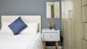 Una camera da letto con un letto, un comodino con uno specchio, una pianta in vaso e un armadio.