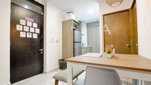 Una cucina moderna con forno e microonde integrati, una porta in legno con una grande lettera 'A', e un'area pranzo con tavolo e panchina.