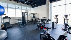 A gym with various exercise equipment, including treadmills, weight machines, and dumbbells.