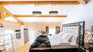 A bedroom with a large bed, wooden beams, a chandelier, and a decorative headboard. - Suite Ravenna : Charm, Cathedral height & Luxury, Swimming pool - Domaine de Pagnon (Saint-Gervais)