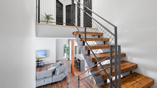 Un intérieur moderne avec un escalier en bois, un canapé gris et un téléviseur à écran plat.