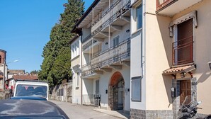 A multi-story building with balconies, a stone archway entrance, and a parked motorcycle. - Apartment 'Azalea' with Lake View, Wi-Fi and Air Conditioning (Laveno-Mombello)