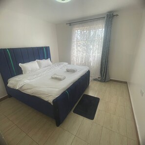 Ein Schlafzimmer mit einem Bett, einem Fenster mit Vorhängen und einem kleinen Teppich.