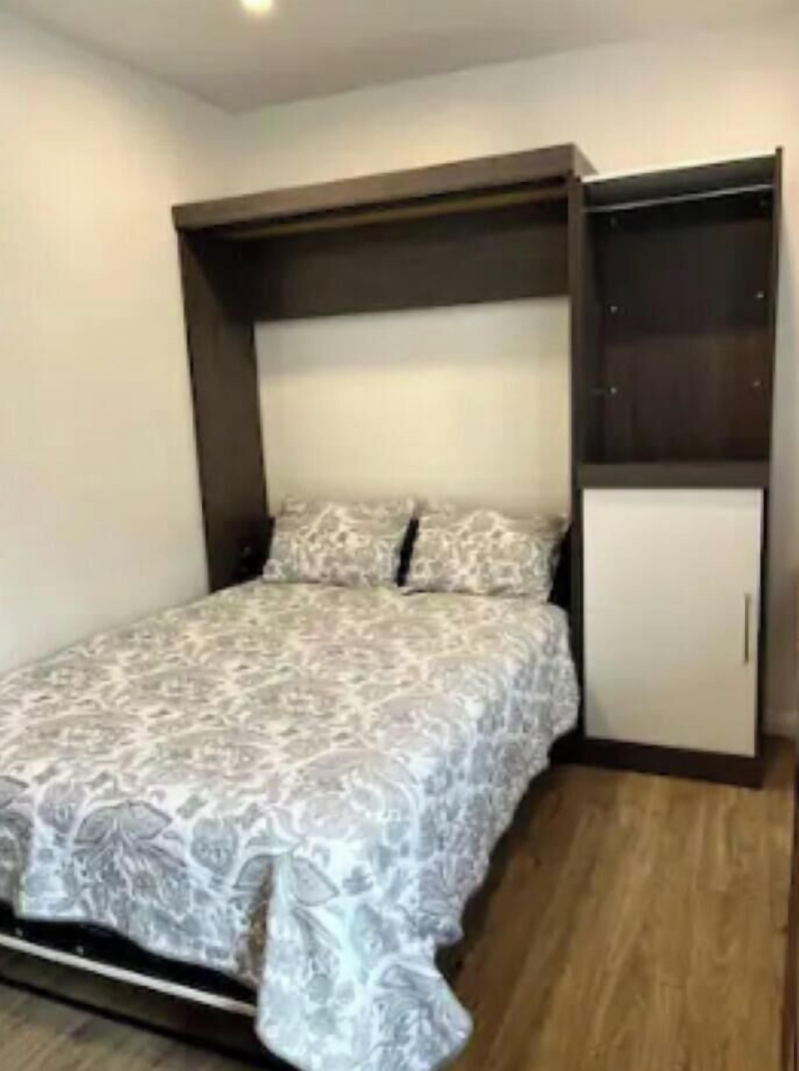 A bedroom with a bed, a wardrobe, and a built-in shelf.