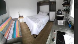A compact room with a bed, a small kitchenette, and a sofa. - Amazing Studio in Pasadena! (Pasadena)