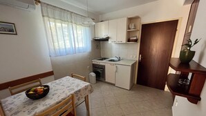 A compact kitchen with a dining table, chairs, a sink, and cabinets. - Cozy 1-bedroom apartment in quaint Lumbarda with AC (Lumbarda)