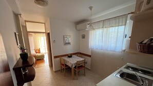 A compact kitchen with a dining table, a sink, and a window with curtains. - Cozy 1-bedroom apartment in quaint Lumbarda with AC (Lumbarda)