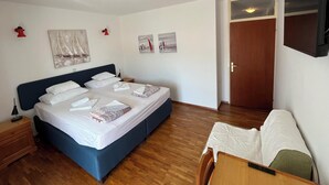 A neatly made bed with white linens, a bedside table with a lamp, and a wooden floor. - Cozy 1-bedroom apartment in quaint Lumbarda with AC (Lumbarda)