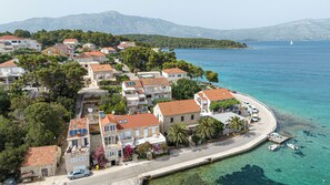 A coastal residential area with houses, clear blue sea, and mountains in the background. - Enjoyable 1-bedroom apartment with AC in charming Lumbarda (Lumbarda)