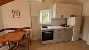 Cocina compacta con mesa y sillas de madera, horno empotrado y ventana con vistas.