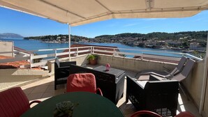 Una terraza con mobiliario exterior, vista a un cuerpo de agua y un pueblo lejano.