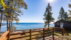 Eine Holzterrasse mit Blick auf das Meer und eine Hütte.