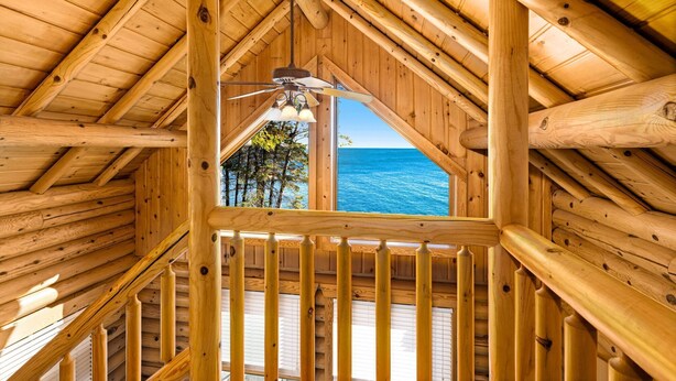 Eine Holzhütte mit geneigtem Dach, einem Deckenventilator und Meerblick durch ein Fenster.