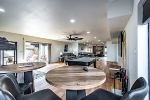 Una sala de estar moderna con mesa de billar, sillones de cuero y ventilador de techo.