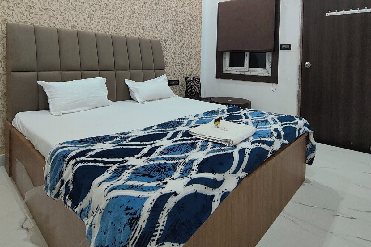 A hotel room with a bed, a bedside table, a wall-mounted TV, and a door.