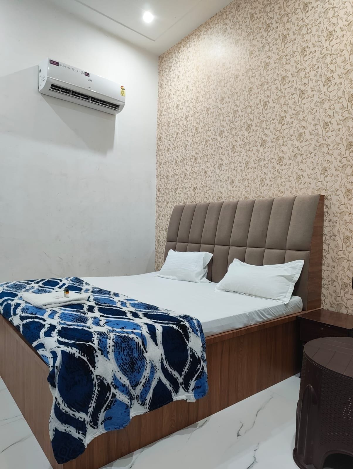 Une chambre à coucher avec un lit, un climatiseur fixé au mur et un papier peint à motifs.
