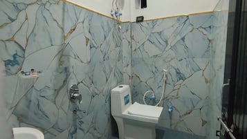 A bathroom with a toilet, sink, and a blue bucket on the floor.