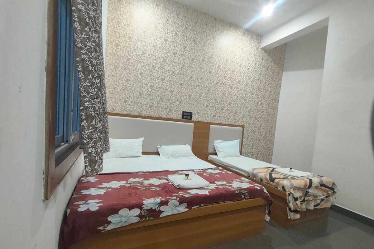 A double bed with a floral bedspread, a wooden headboard, and a nightstand with a patterned cloth.